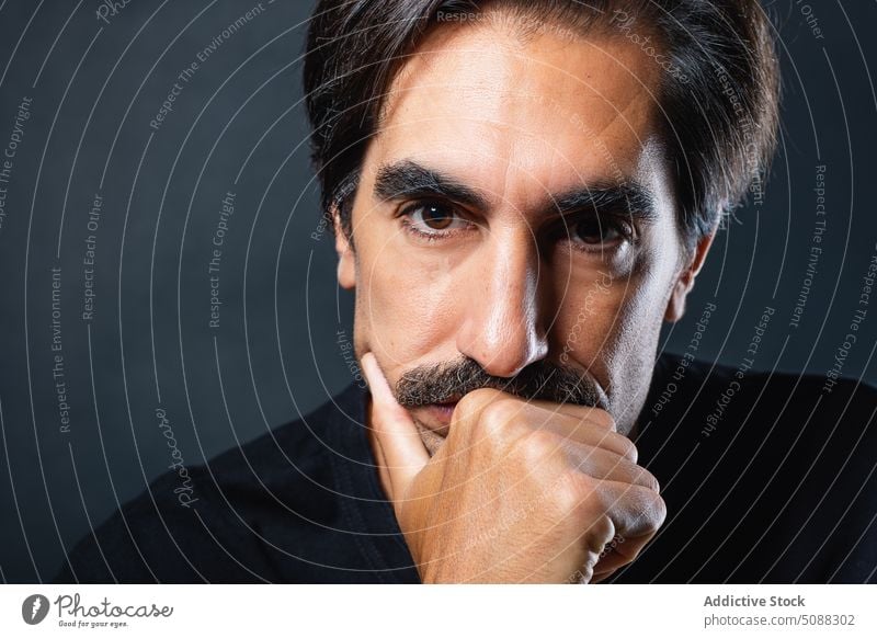 Serious man with mustache on black background portrait serious masculine individuality personality studio shot emotionless unshaven male adult appearance