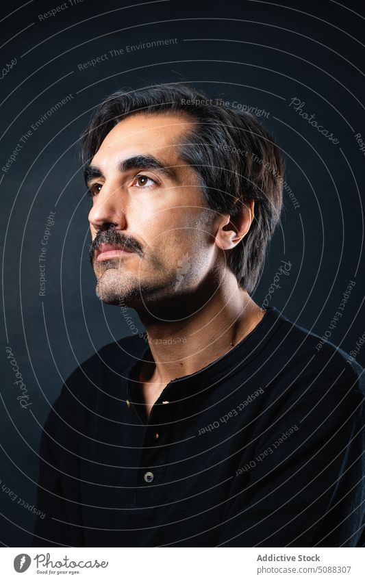 Serious man with mustache on black background portrait serious masculine individuality personality studio shot emotionless unshaven male adult appearance