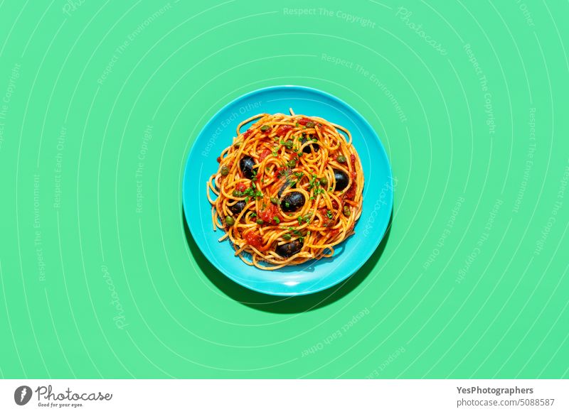 Spaghetti puttanesca plate, above view on a green background bright capers carbs color cooked copy space creative cuisine cut out delicious dinner dish food