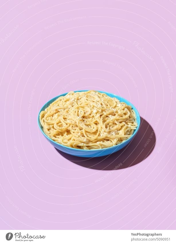 Spaghetti cacio e pepe in a bowl on a purple background above bright carbs cheese color cooked copy space creative cuisine cut out delicious dinner dish eating