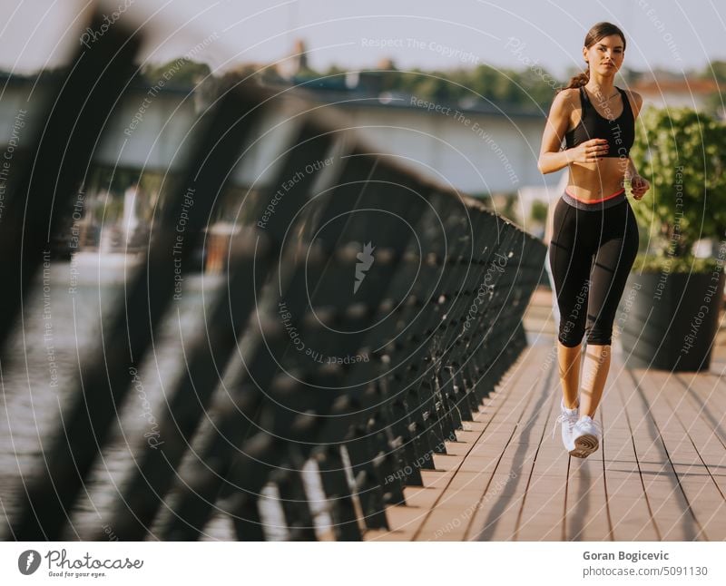 Active young beautiful woman running on the promenade along the riverside active activity athlete athletic city endurance exercise female fitness healthy into