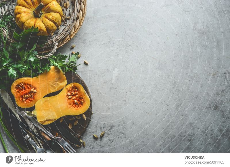 Healthy seasonal food background with pumpkins, fresh herbs and cutlery  on rustic background, top view. Border healthy border autumn overhead thanksgiving