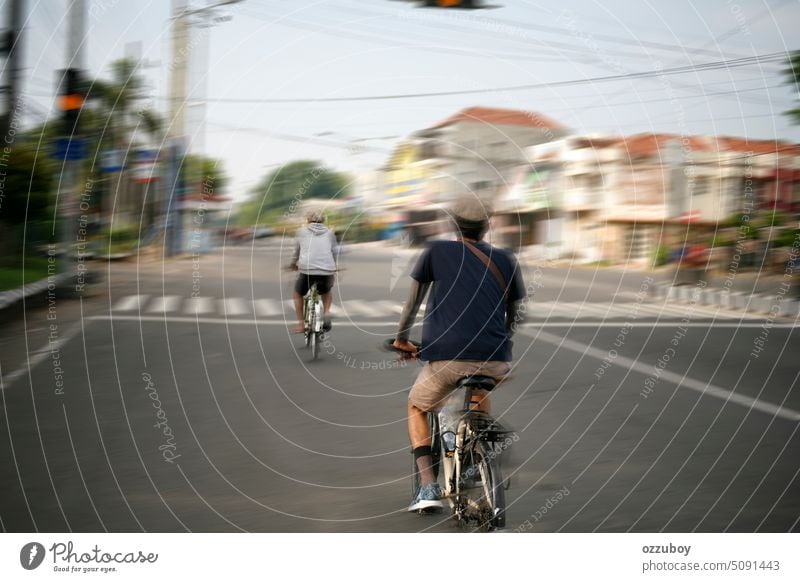 motion blur of two person riding bicycle in asian street. rear view. man bike road outdoor ride male sport city speed cyclist lifestyle transport healthy