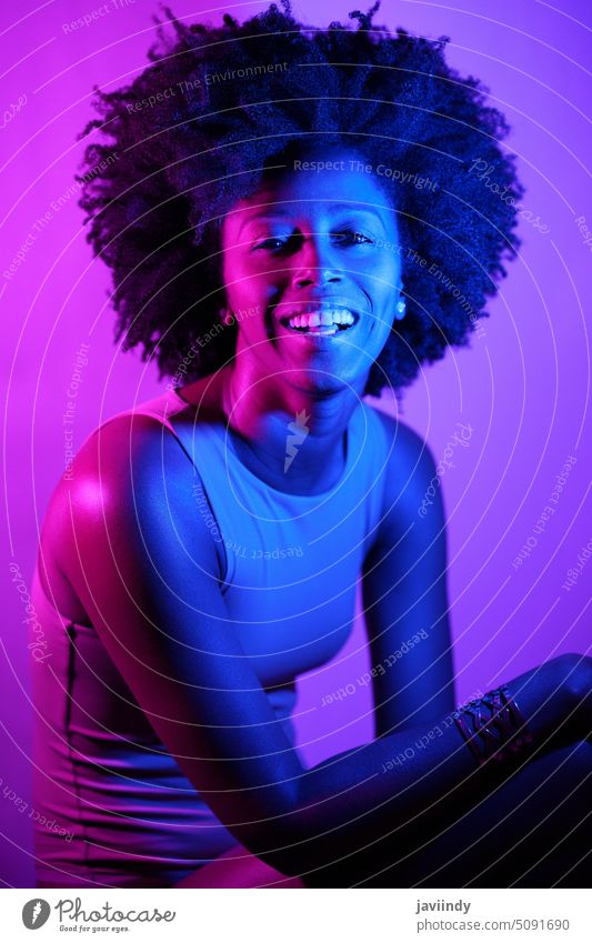 Cheerful black model looking at camera woman style neon illuminate color smile happy bright portrait female young african american ethnic glad individuality