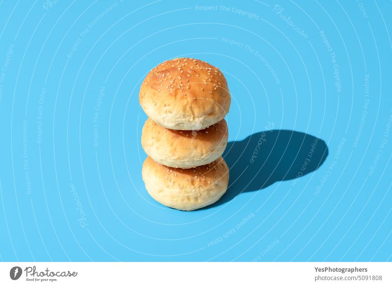 Bread buns in bright light isolated on a blue background above baked bakery balls bread breakfast burger cheeseburger close-up color crust cuisine cut out