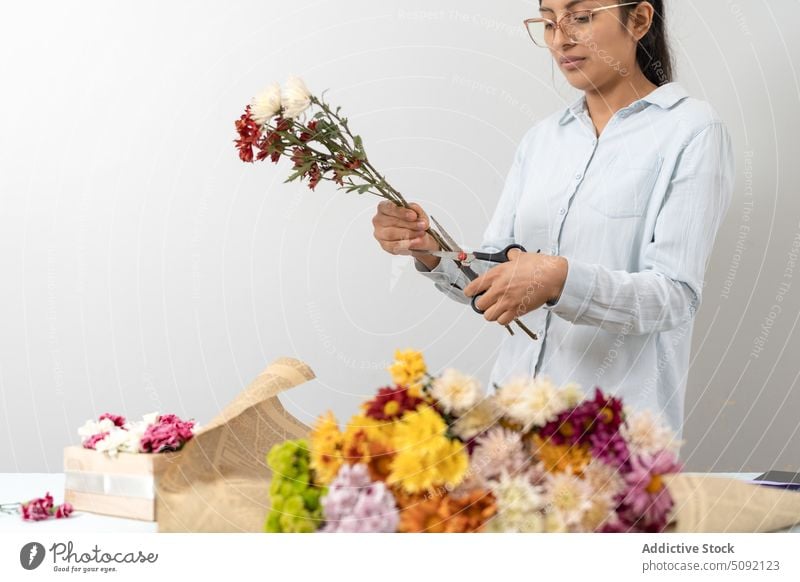 Positive female florist arranging bouquet of flowers woman cut stem arrange craft paper festive present creative floral floristry small business order romantic
