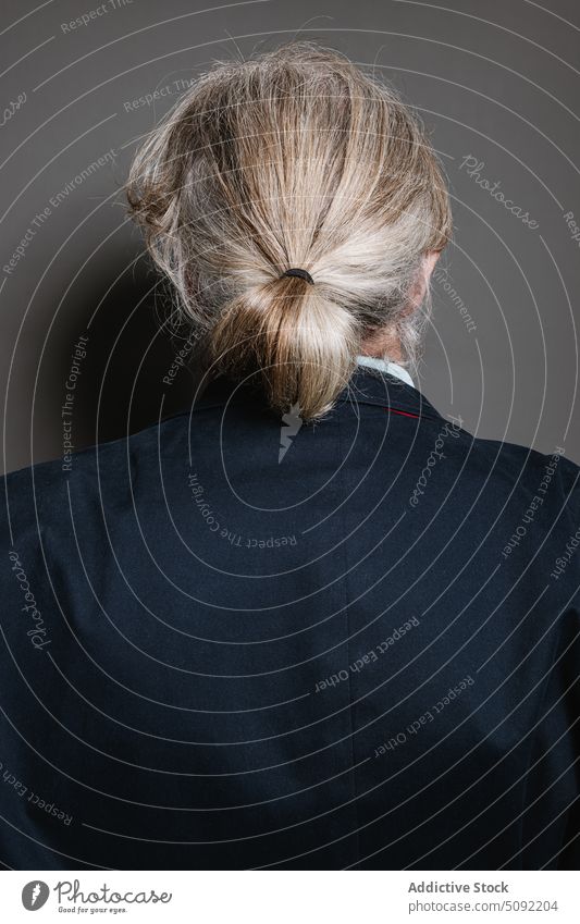 Senior gray haired man standing with back turned studio shot gentleman ponytail suit jacket intelligent hairstyle senior elderly aged male classic pensioner