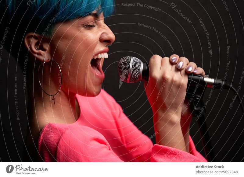 Young woman singing into microphone song singer music perform style talent skill eyes closed voice sound young melody female casual device loud entertain