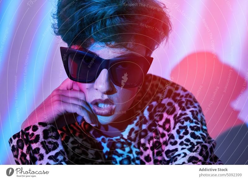 Stylish woman in sunglasses with neon lights portrait trendy style model confident attitude colorful outfit wall appearance modern female individuality young
