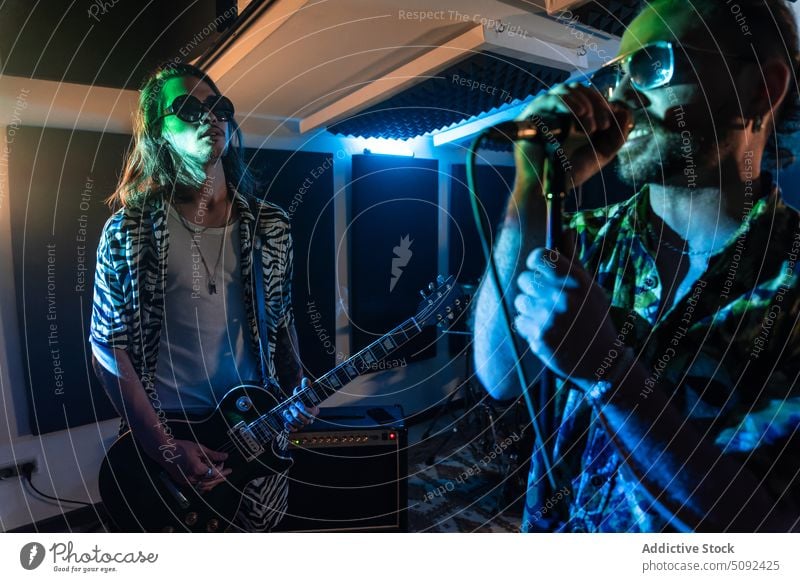 Stylish rock band performing in club at night men singer guitarist play music rehearsal musician electric style studio confident talent trendy sunglasses male