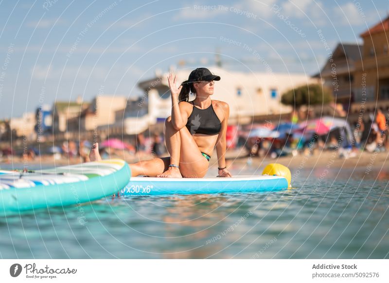 Healthy female sitting on paddleboard and doing yoga woman practice asana sup board sea nature water harmony resort summer activity vakrasana