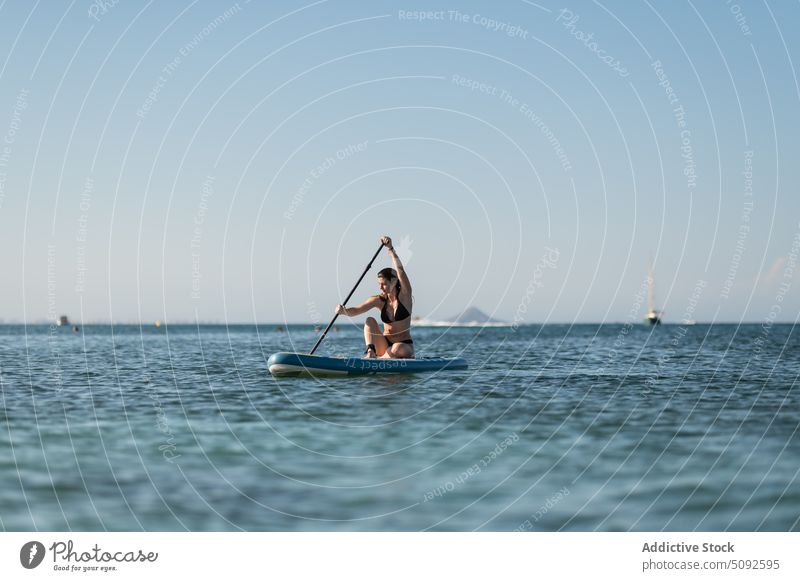 Tourist rowing while floating on sup board in sea tourist paddleboard ripple water tranquil cloudless woman sky hobby nature summer ride recreation endless