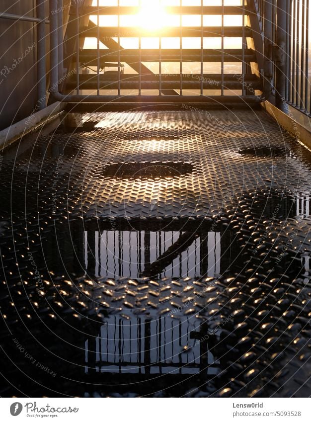 A sunset behind a metal staircase with puddles of water in the foreground background Construction Dark Dusk Factory Industrial Industry Metal Puddle Stairs