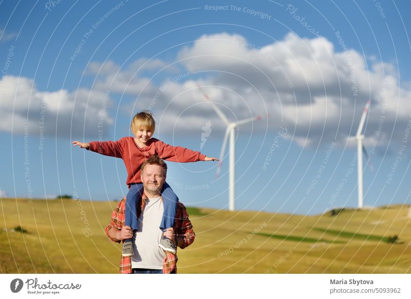 Eco activists man and child on background of power stations for renewable electric energy production. People and windmills. Wind turbines for generation electricity. Green energy