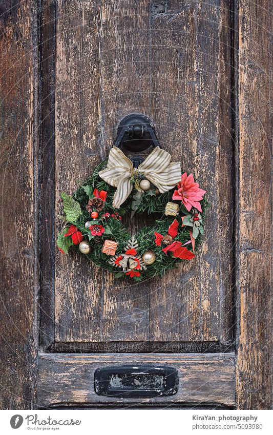 Christmas crown wreath upon an old wooden door. Traditional home decor during Christmas christmas decoration natural vintage diy festive object closeup