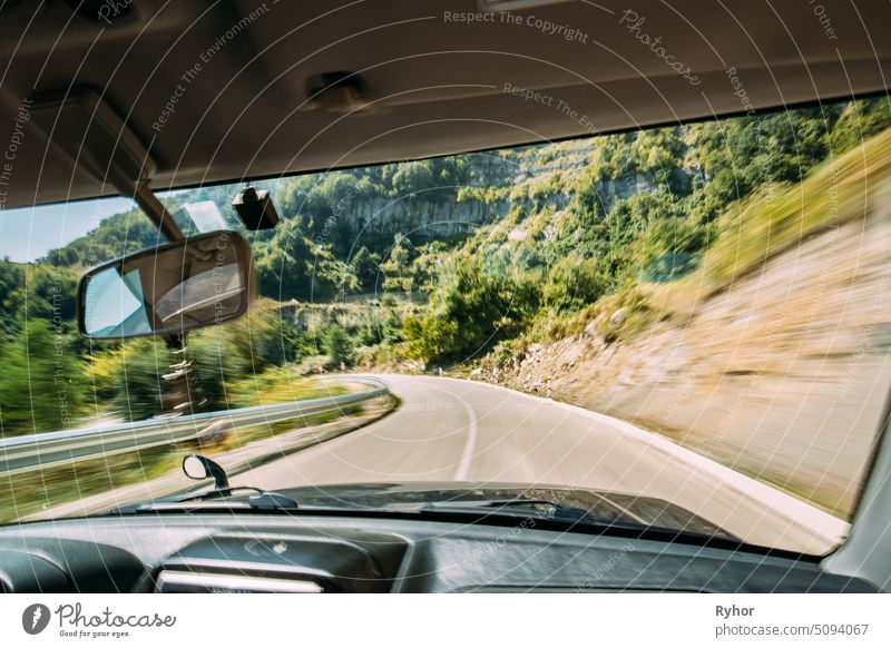 View From Vehicle Car Interior To Blurred Background Of Road In Fast Motion. Dangerous Fast Motion Movement In Route. Summer Asphalt On Mountain Road Motorway Highway. Travel Concept