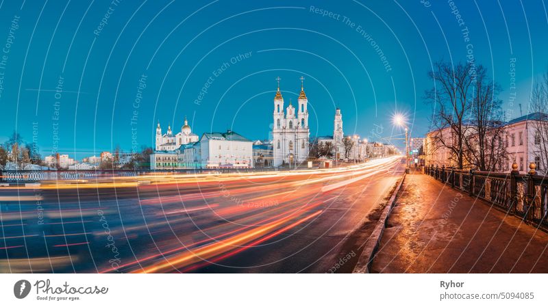 Vitebsk, Belarus. Evening Or Night View Of Famous Landmarks Is Assumption Cathedral, Church Of Resurrection Of Christ And Old Town Hall In Street Lights Illumination. Traffic Light Trails