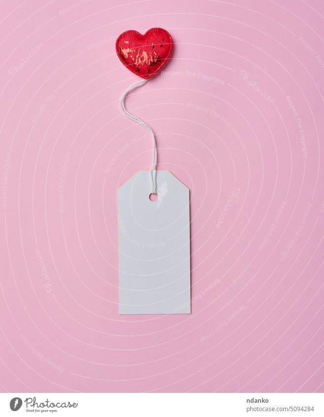 Blank white cardboard tag on white rope, pink background red heart paper label string sale blank price retail empty gift sell hang pricing buy recycled shipping