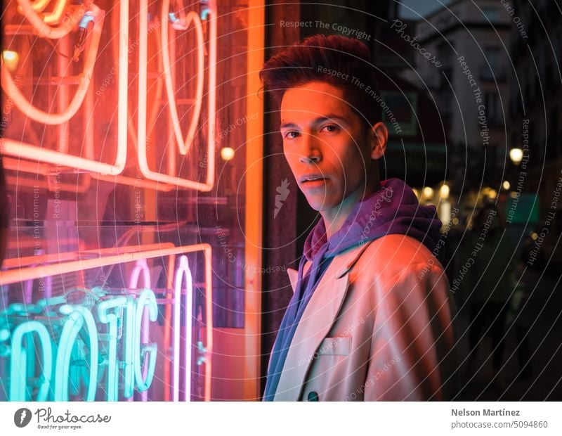 Portrait of young hispanic man with red neon light on the face, wearing a beige blazer street bright fashion suit party look leather night guy concept colourful