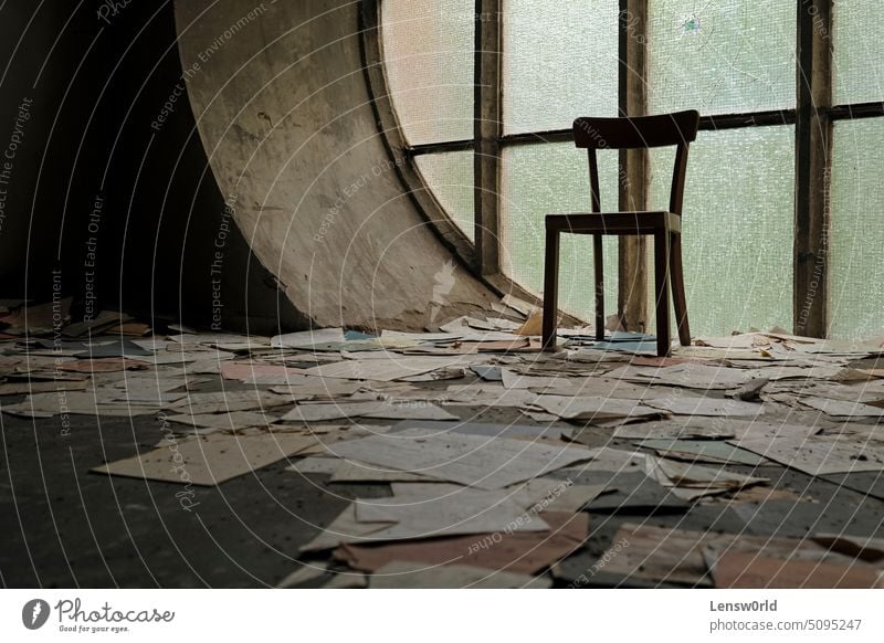 Chair in front of a round window in an abandoned church with papers and book pages lying on the ground abandoned house background building chair church interior