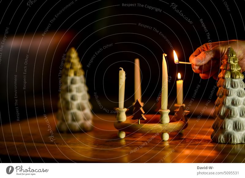 Man lights candles for advent Christmas & Advent Advent candles Christmas wreath Ignite advent season Match Hand Candlelight Festive Minimalistic unostentatious