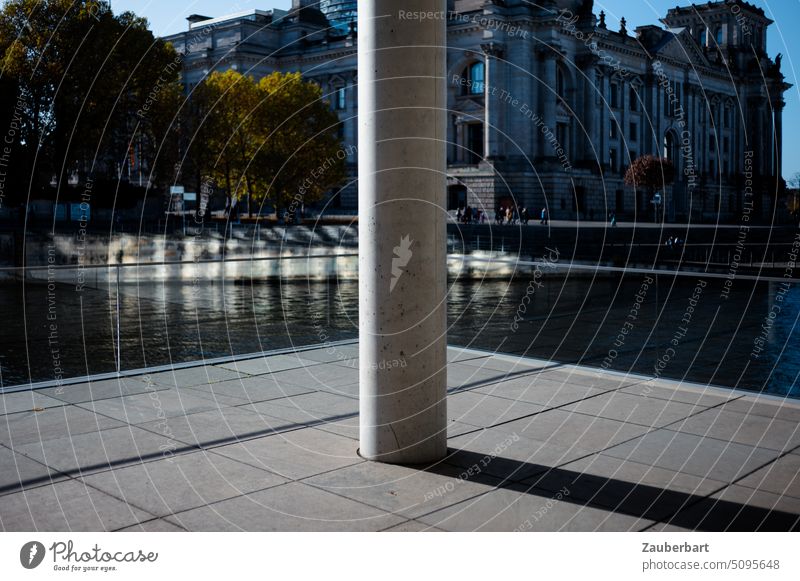 View of a column in front of the Spree river bank, behind it the Reichstag, in Berlin government district Column Bundestag government quarter bank of the Spree