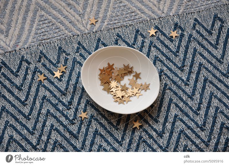 Golden stars lie in a porcelain bowl and on a patterned tablecloth. Decoration Christmas decoration Christmas & Advent Winter Feasts & Celebrations Tradition