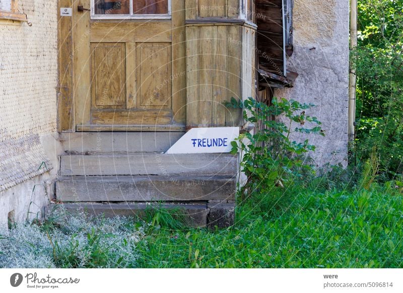 Wooden door on an old wooden house with a sign with German text: Friends Invitation Saying building copy space entrance friends funny german nobody slogan