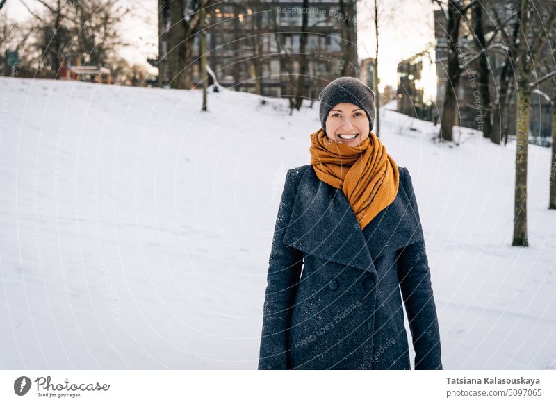 A young woman in winter clothes smiles broadly looking into the camera cold snow happiness happy joy female people person adult coat Single person cheerful
