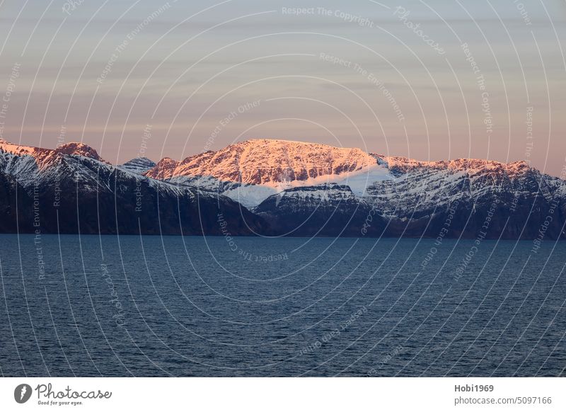 Sunrise on the coast near Alta in Norway. The mountains are illuminated by the sun. Fjord Snow snow-covered Europe Water salt water Sea water ocean Cold chill