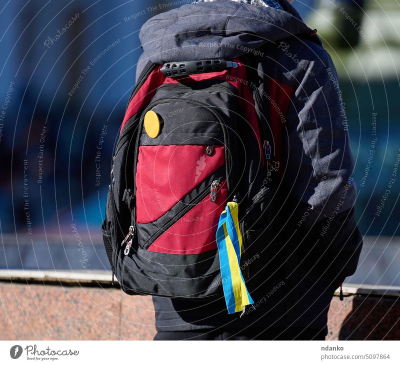 A yellow-blue ribbon is tied on a man's backpack, November 2022 Kherson kherson ukraine symbol solidarity support war national patriot ukrainian conflict