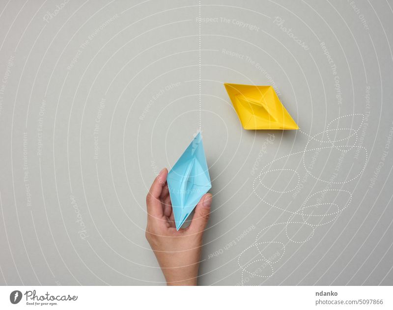 Paper boats with different trajectories on a gray background. The concept of extraordinary thinking hand blue leadership line long metaphor optimal origami