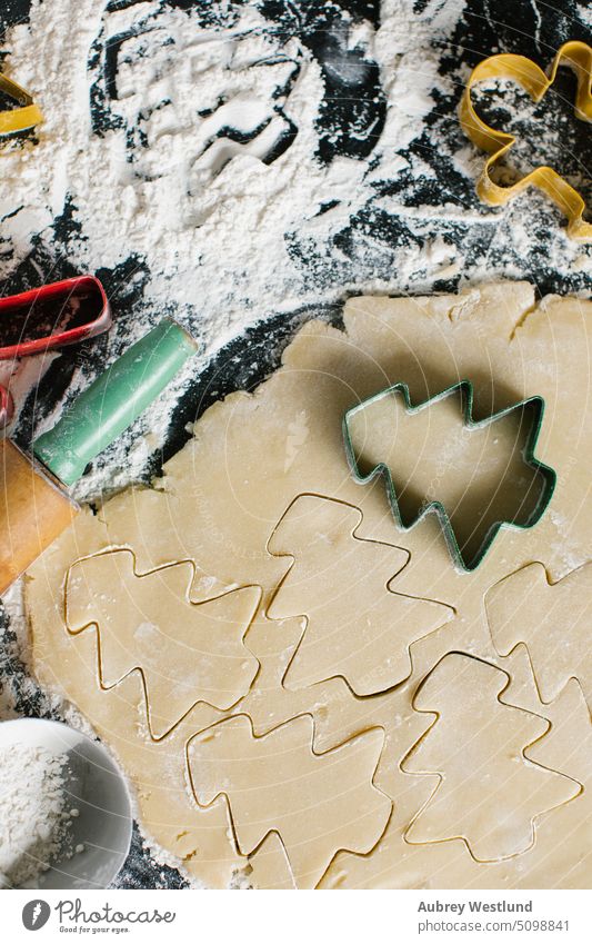 Christmas tree cookies being cut from freshly pressed dough bake baking baking sheet black candy cane celebration childhood children christmas christmas tree