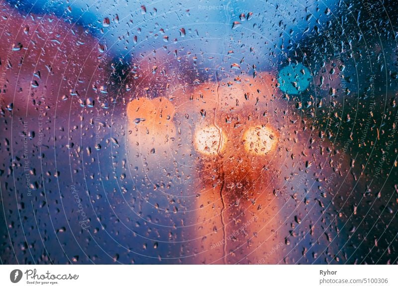 Water Drops Of Rain On Glass Background. Street Bokeh Lights Out Of Focus. Autumn Abstract Backdrop Concept textured window light background street yellow rain