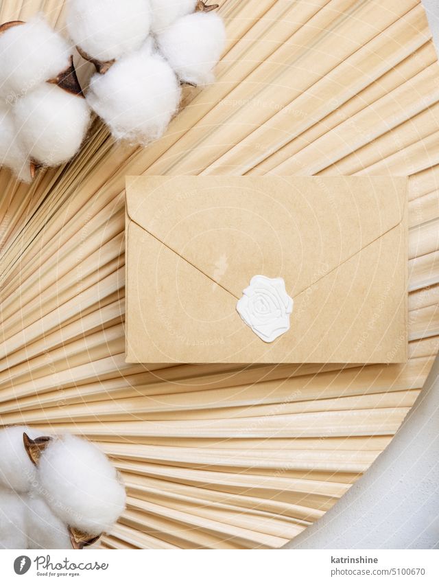 Sealed envelope on dried palm leaf with cotton flowers from top, wedding mockup Wedding Envelope Mock-up Beige Palm of the hand Leaf Cotton plant Flower