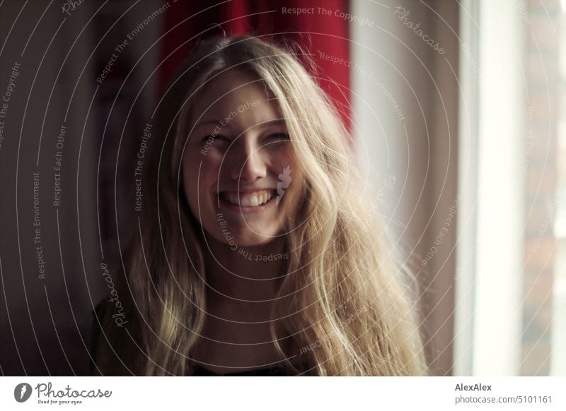 Close portrait of young blonde woman standing at window smiling Woman Young woman Blonde Long-haired Smiling Joy Window Slim kind Pleasant pretty Attractive