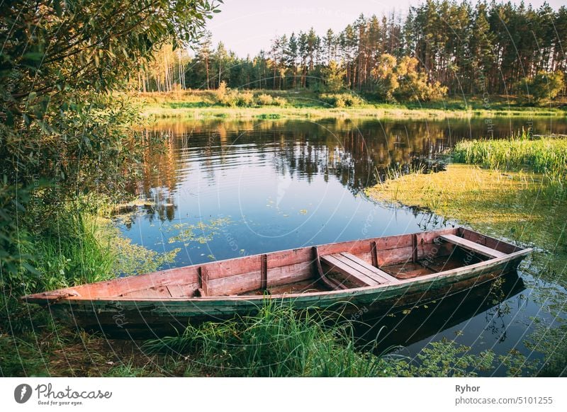 Old Wooden Rowing Fishing Boat Near Lake River Coast At Beautiful Summer Sunny Day. summer lake park nobody wooden beautiful belarus russia europe row boat calm