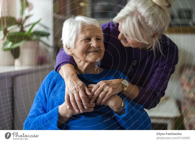 Woman hugging her elderly mother smiling happy enjoying positive people woman senior mature female home house old aging domestic life grandmother pensioner