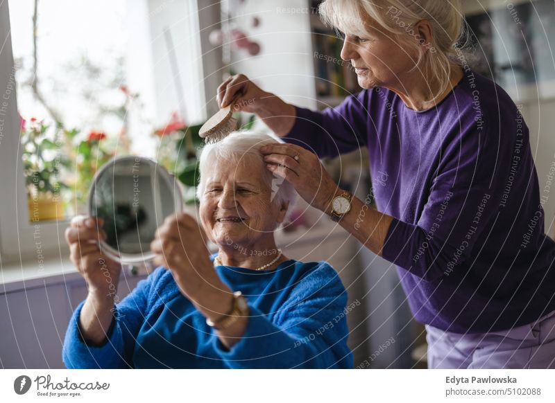 Woman combing hair of elderly mother smiling happy enjoying positive people woman senior mature female home house old aging domestic life grandmother pensioner
