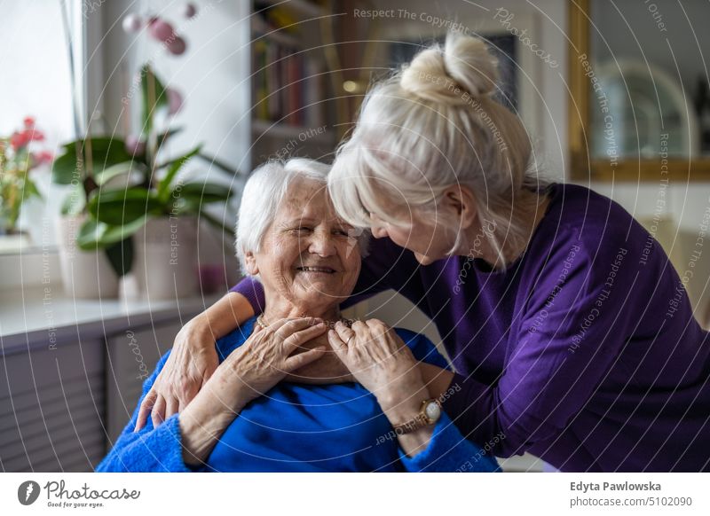 Woman hugging her elderly mother smiling happy enjoying positive people woman senior mature female home house old aging domestic life grandmother pensioner
