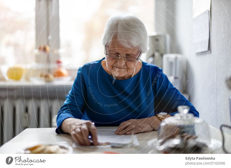 Senior woman filling out financial statements smiling happy enjoying positive people senior mature female elderly home house old aging domestic life grandmother