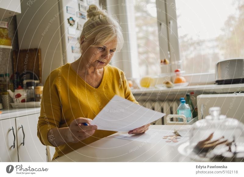 Senior woman filling out financial statements people senior mature female elderly home house old aging domestic life grandmother pensioner retired retirement