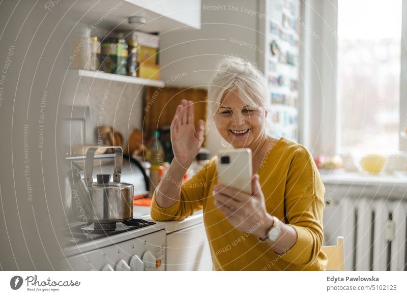 Senior woman using mobile phone at home smiling happy enjoying positive people senior mature female elderly house old aging domestic life grandmother pensioner