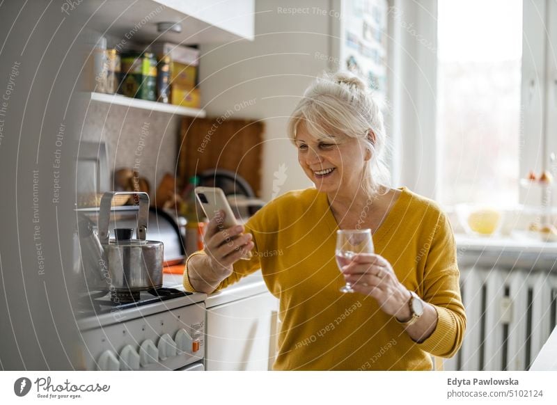Senior woman using mobile phone at home smiling happy enjoying positive people senior mature female elderly house old aging domestic life grandmother pensioner
