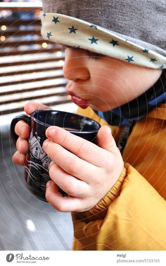Close up of boy holding cup of hot chocolate in hands and blowing at Christmas market Human being Boy (child) Child Close-up portrait Head Face Cup