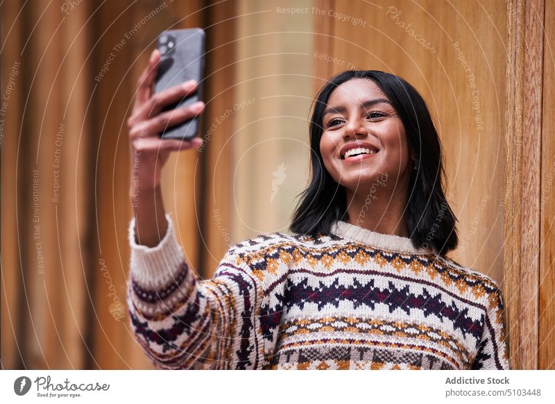 Cheerful black female taking selfie woman smile lean wall smartphone style sweater happy social media young ethnic positive cellphone memory glad cheerful