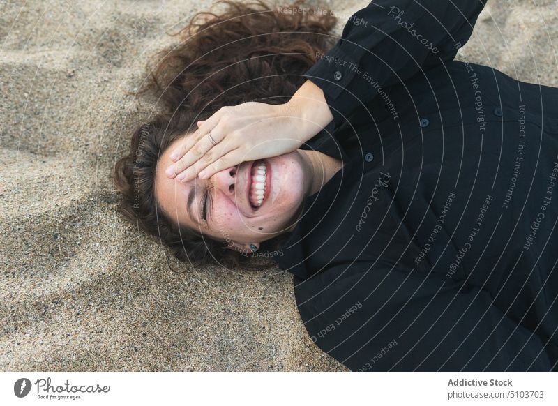 Cheerful woman covering eye while lying on sand beach joy coast leisure chill cover eye having fun cheerful smile happy positive female young relax rest