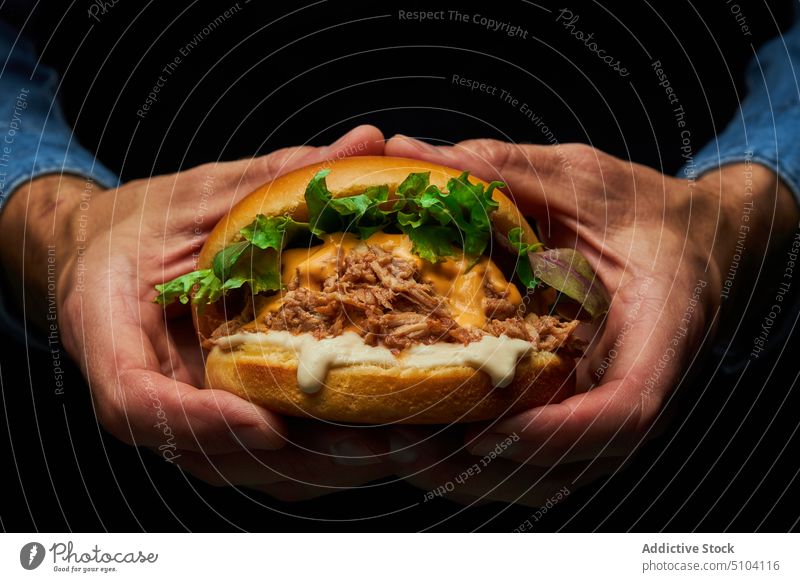 Crop person with delicious burger hand fast food junk food culinary meal unhealthy calorie lettuce pork bun meat flavor palatable taste ingredient