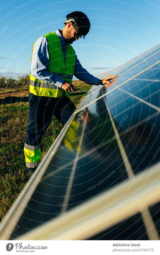 Worker installing photovoltaic cells in daylight man technician solar panel renewal sustainable alternative eco friendly energy male professional countryside