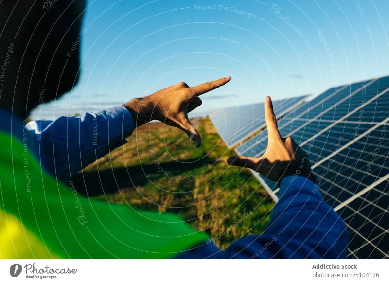 Crop employee showing frame gesture against solar panels technician worker photovoltaic battery renewal sustainable alternative photo gesture energy